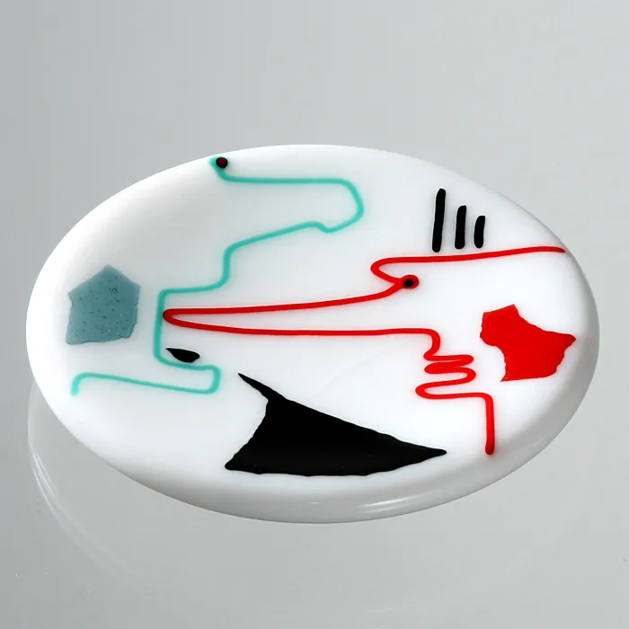 Runder Glasteller mit farbigen Linien und Flächen